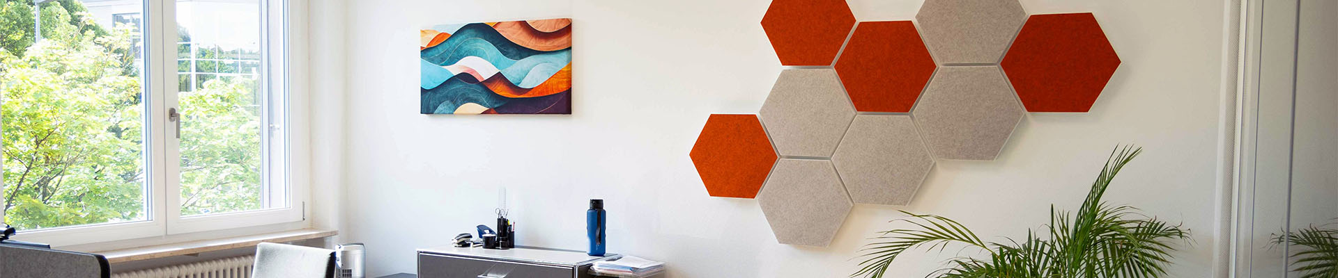 Sechseckige Schallschutzelemente hängen an einer Wand eines Büros